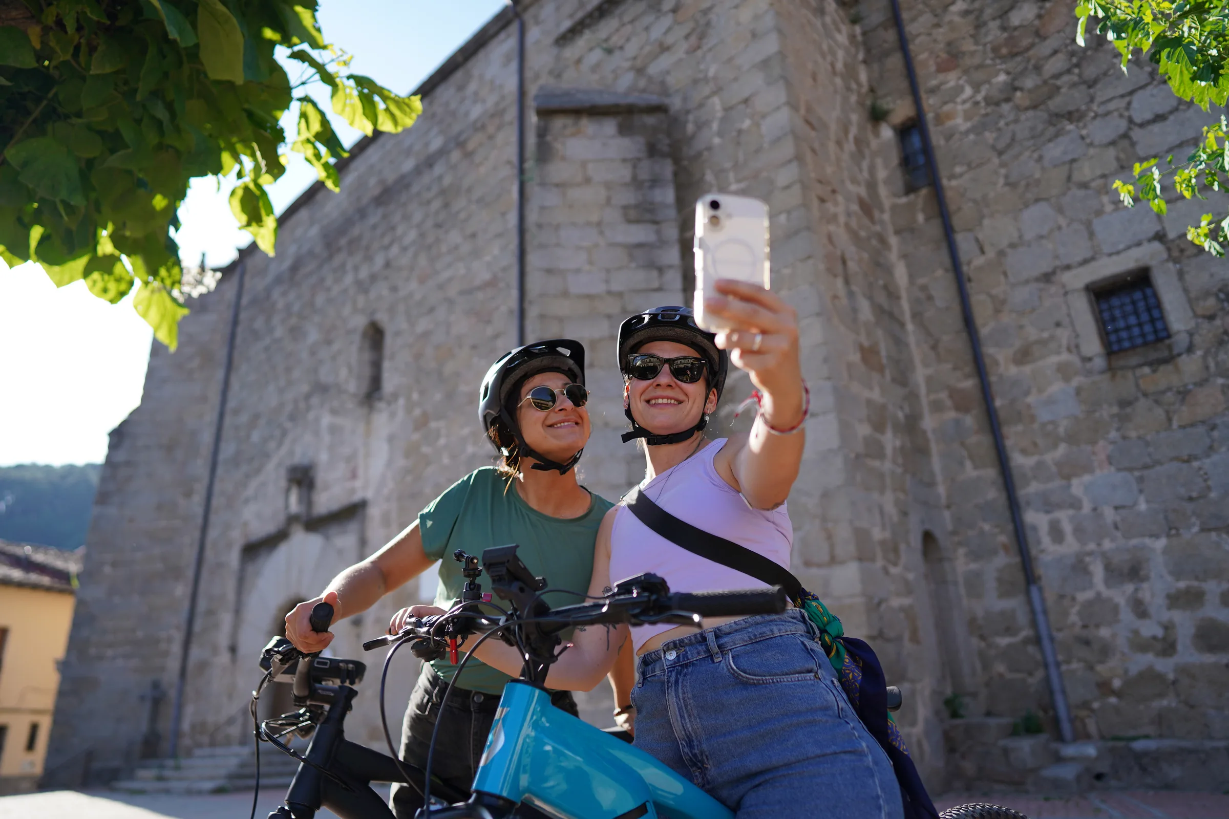 Ciclistas con e-bikes frente a un monasterio de piedra en Gredos